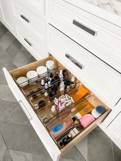 an open drawer in a bathroom filled with cosmetics and personal care items on the counter