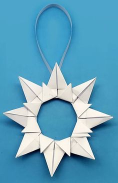 a white origami star decoration hanging on a blue background with a ribbon around it