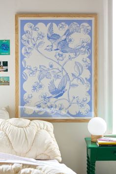 a blue and white bird print hanging above a bed