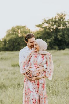 a man and woman are standing together in the grass with their arms around each other