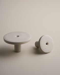 two white ceramic knobs sitting next to each other on top of a gray surface