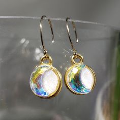 "One of a kind clay (white blend) and resin (creates a glass like finish) dangling earrings. Embellished with an embedded Austrian crystal (crystal ab crescent moon) in a 15x11mm gold plated pewter bezel. Approximate length 1\". Hung on gold filled end ball ear wires. Be like the moon. The moon reminds us to see beauty in darkness.  Her glow takes many shapes, embracing individuality and change. She is beautiful in all forms. She is unique, authentic and true. Photos taken in studio light.  Free U.S. shipping on orders over $35. International shipping available. Same item as shown, contact me for free sizing adjustments. Shipped in a sealed and protected plastic bag. Free customer consultation offered to create a client profile I keep on hand with measurements and preferences for future or Iridescent Drop Earrings With Matching Jewelry, Iridescent Drop Earrings With Matching Jewelry Set, Iridescent Drop Earrings Jewelry Set, Iridescent Jewelry With Matching Drop Earrings, Modern Resin Drop Earrings, Glass Drop Crystal Earrings For Gift, Gold Moon-shaped Crystal Earrings Gift, Gold Moon Shaped Crystal Earrings For Gift, Gold Resin Jewelry With Ear Wire