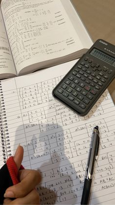 a person is writing on a notebook with a calculator