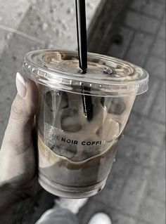 a person holding up a plastic cup filled with coffee