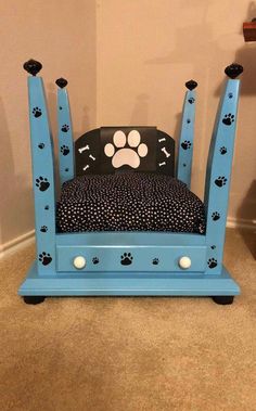 a blue dog bed with paw prints on the back and paws on the sides, sitting in front of a wall