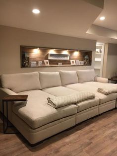 a living room with a large sectional couch in the center and shelves on the wall