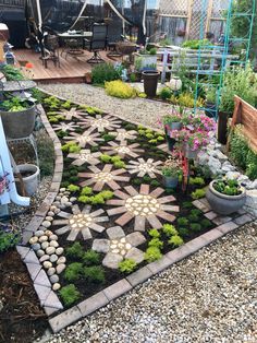 an outdoor garden with flowers and plants in the center, surrounded by graveled walkways