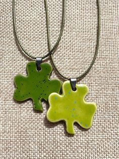 This necklace is a unique, handcrafted piece of jewelry...ready to stand out!  Wear it as a lucky charm and avoid getting pinched on St. Patrick's day! Dimensions Pendant: 3 leaf  W 1 5/8" x H 1 1/2" 4 leaf pendant is slightly smaller Thickness app 1/8" Color Pictured: Green thumb speckled, Sour apple speckled Necklaces are 18" green cording Nickel free Necklaces may vary depending on availability. Handmade in North Carolina Longer or different necklaces are available upon request.  I try to make each pendant a unique, handcrafted, & quality piece of jewelry for you. I ensure that they are flat, light weight, that the edges are soft, and the glaze application is even. Warning: Please keep away from small children and pets. The necklaces may present a choking hazard. The pendant is made out Green Charms Jewelry For Good Luck, Nickel-free Green Flower Pendant Jewelry, Green Good Luck Charms Necklace, Green Nickel-free Pendant Charm Necklace, Personalized Green Charm Necklace With Round Pendant, Personalized Green Round Pendant Charm Necklace, Personalized Green Round Pendant Necklace, Adjustable Green Necklace As Gift, Lucky Charm Necklace