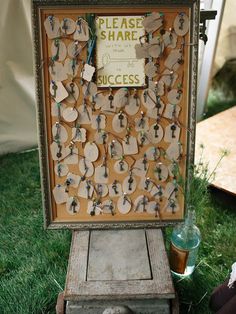 an old wooden board with lots of tags attached to it on the grass in front of a tent