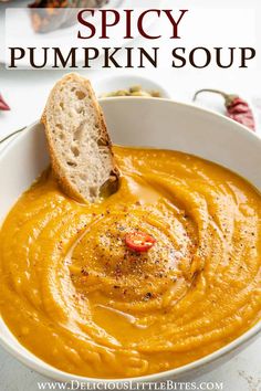 a white bowl filled with pumpkin soup and a piece of bread sticking out of it