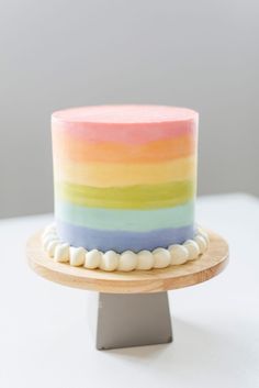 a multicolored cake sitting on top of a wooden stand