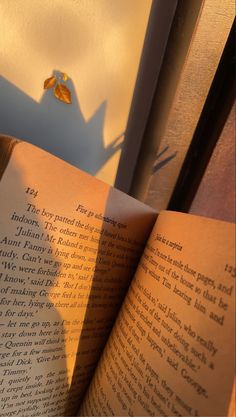 an open book sitting on top of a wooden table next to a shadow of a person