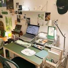 a laptop computer sitting on top of a green desk next to a lamp and chair