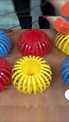 several different colored plastic objects sitting on a wooden table next to a person with an orange object in the background