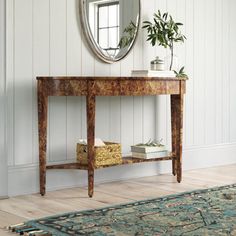 a wooden table with a mirror above it and a rug on the floor next to it