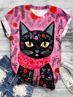 a t - shirt with a black cat on it next to ripped jeans and shoes