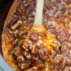 the food is being cooked in the crock pot with a wooden spatula inside