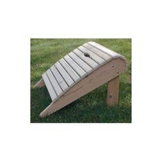 a wooden bench sitting in the grass with one foot on it's side and another leg down