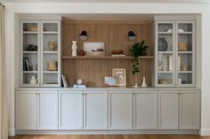 a living room with white bookcases and wooden flooring on the side wall