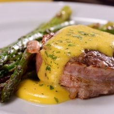 a white plate topped with meat and asparagus