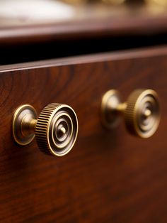 two brass knobs on a wooden drawer