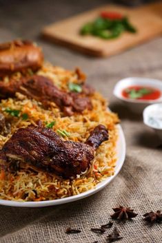 a white plate topped with rice and meat on top of a table next to spices