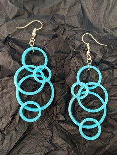 two pairs of blue earrings sitting on top of a black piece of paper next to each other