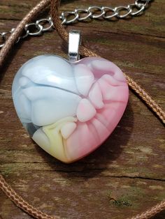 a heart shaped glass pendant sitting on top of a wooden table