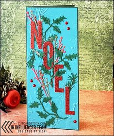 a christmas card with holly leaves and the word noel on it