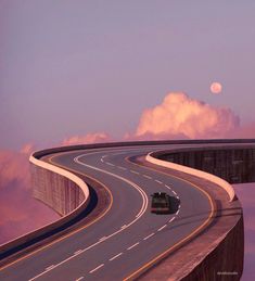 a car is driving down the road in front of a bridge with clouds and a full moon