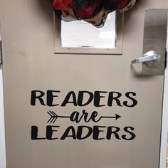 a door with the words readers are leaders painted on it and a wreath hanging above