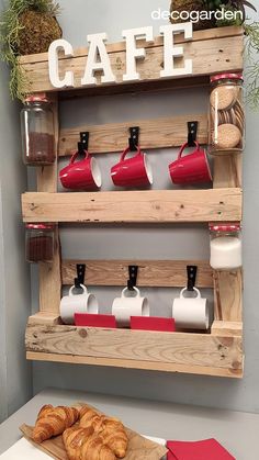 a wooden rack with coffee cups and croissants on it next to a red napkin