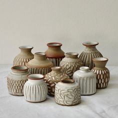 a group of ceramic vases sitting on top of a white tablecloth covered floor