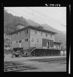 an old black and white photo of a train station with cars parked in front of it