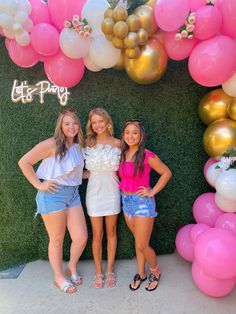 three girls standing in front of a backdrop with balloons