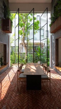 a dining room with brick floors and lots of plants on the windows sills