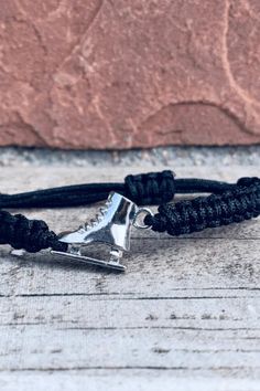 a black cord bracelet with a silver triangle on it