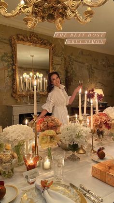 a woman standing in front of a table filled with flowers and candles