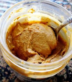 a jar filled with peanut butter on top of a granite counter next to a spoon