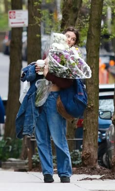 a woman walking down the street carrying flowers