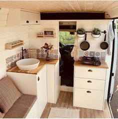 the interior of a camper with wood flooring and white cabinets, including a sink