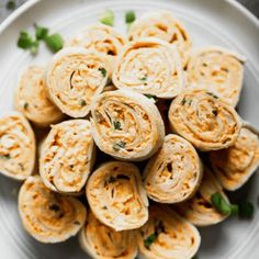 a white plate topped with rolls covered in cheese and garnished with green leaves