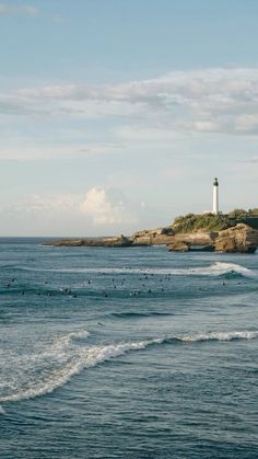 surfers in the ocean near a light house