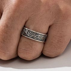 a man's hand wearing a silver ring with leaves on the inside of it