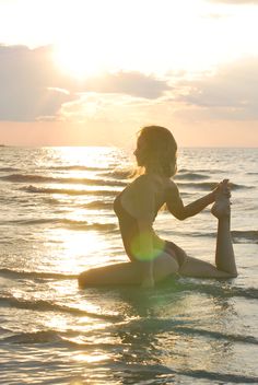 a woman sitting on top of a surfboard in the ocean at sunset or sunrise