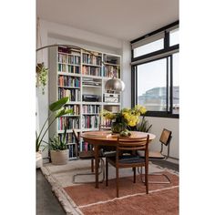 a dining room table and chairs in front of a bookshelf