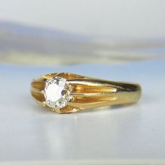 a yellow gold ring with a white diamond on the top and bottom, sitting on a table