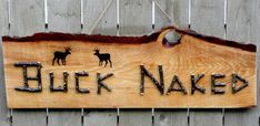 a wooden sign that says buck naked hanging on the side of a fence with two deer