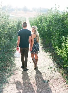 a man and woman walking down a dirt road