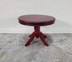 a small round table with four legs and a wooden top, sitting on a marble floor